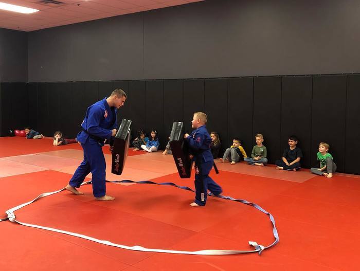 A coach holding kick pads for a student during a Muay Thai class