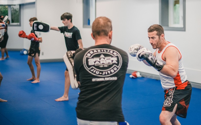 An adult striking focus mitts during Muay Thai pad work